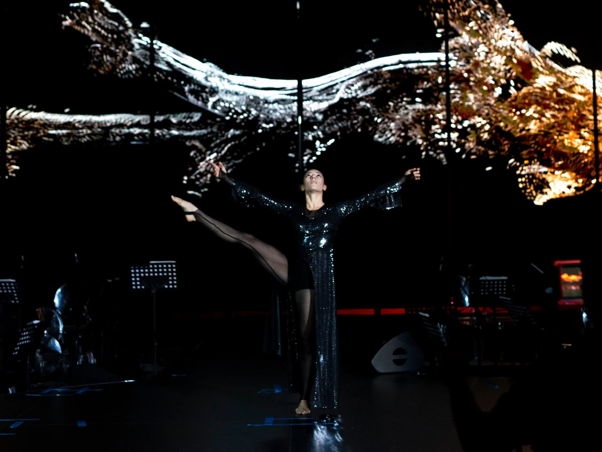 The dancer mid-movement as liquid-metal imagery flows across the screen above her