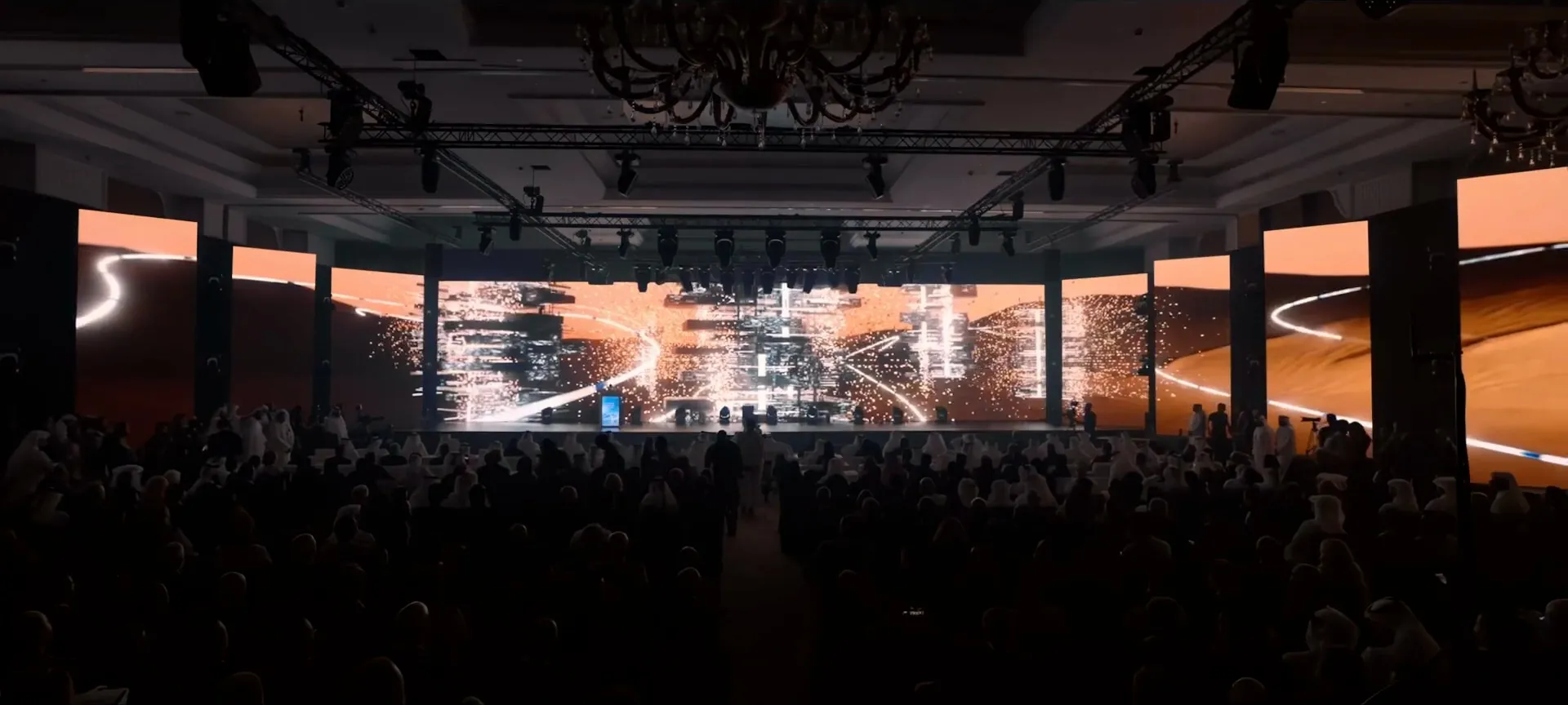 The ballroom glows orange as a light trail sweeps through a city skyline on the panoramic screen