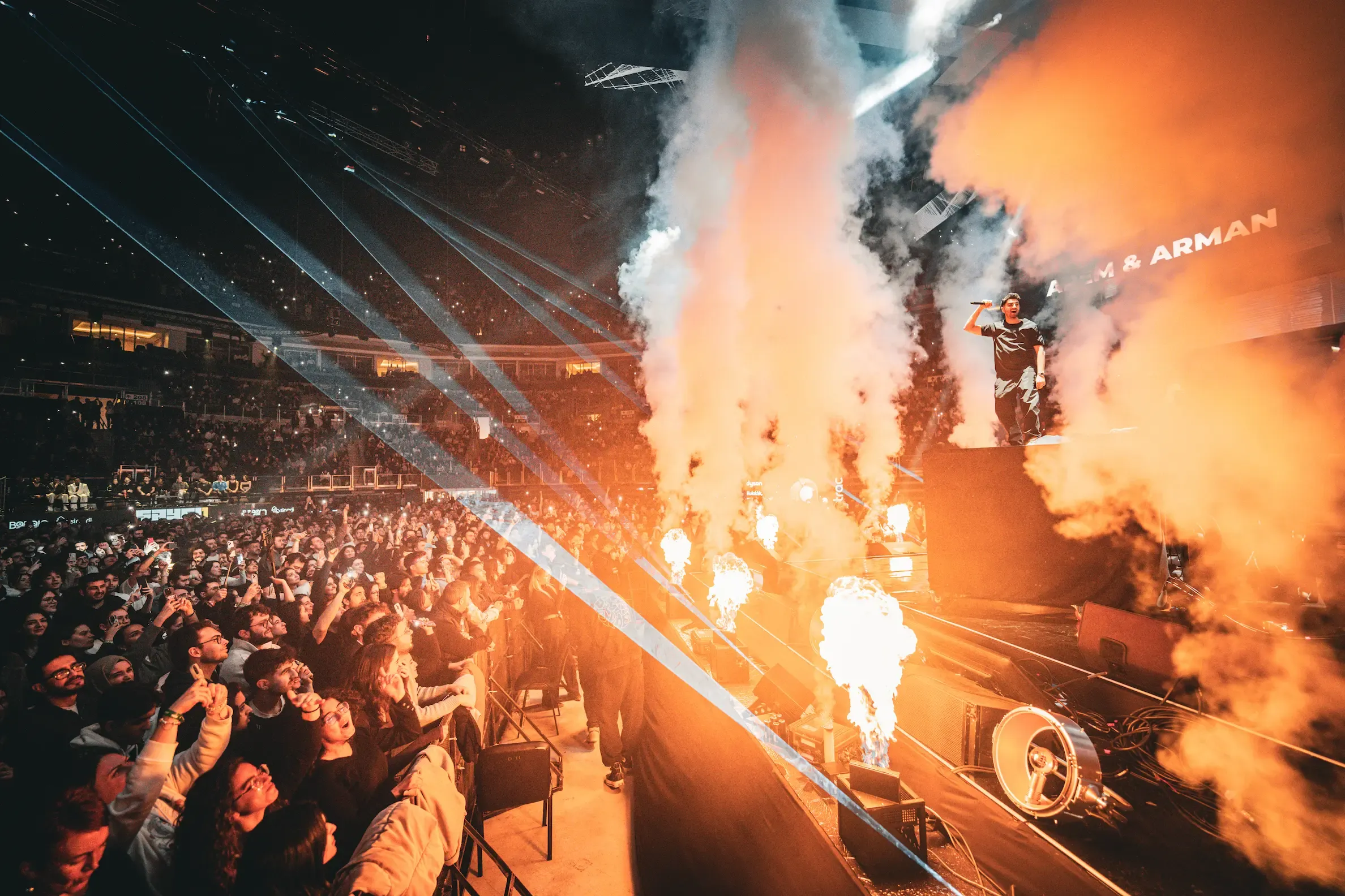 Flame jets and haze on stage as a packed arena raises its hands