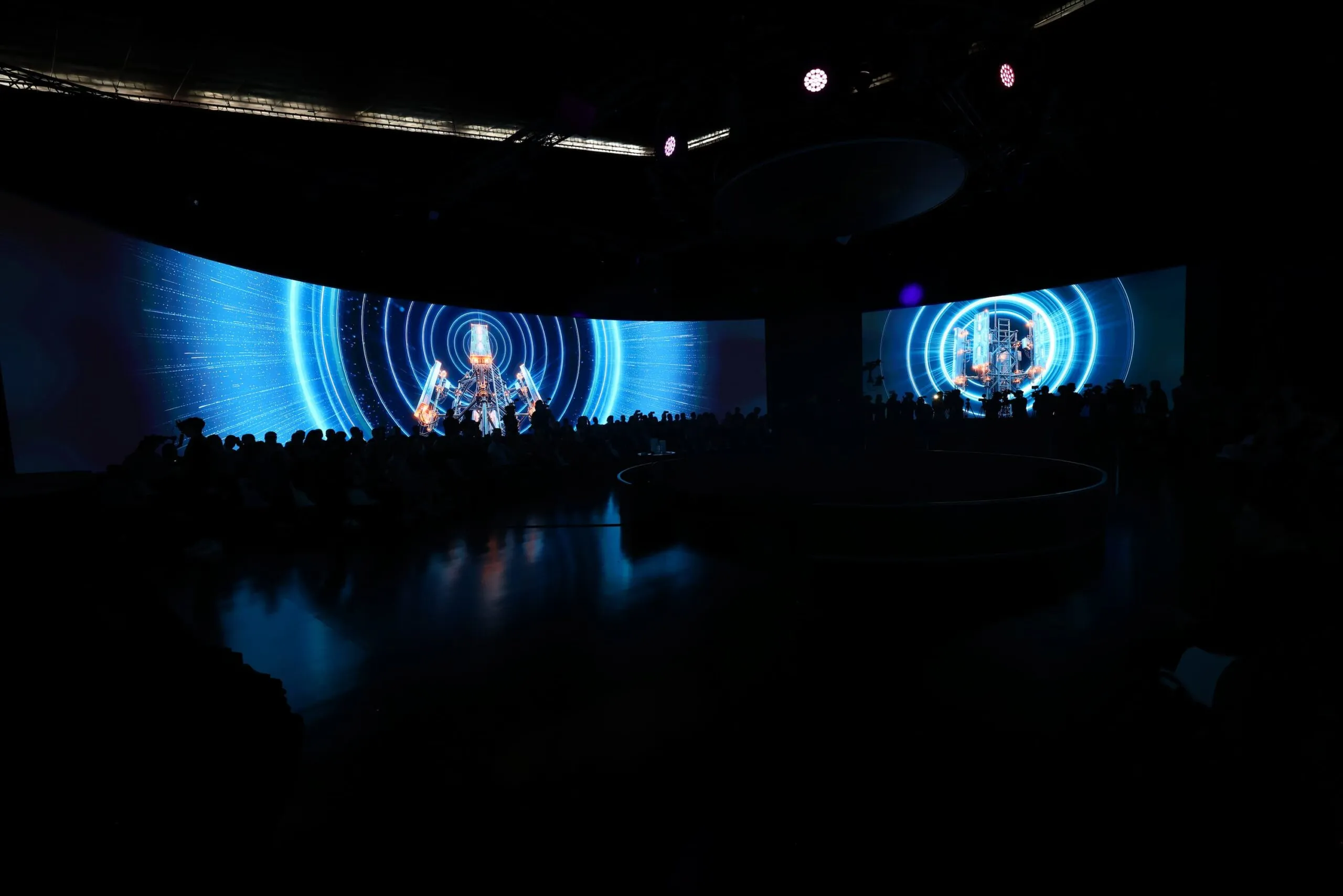 The darkened venue from a distance, the 360° LED wall glowing blue