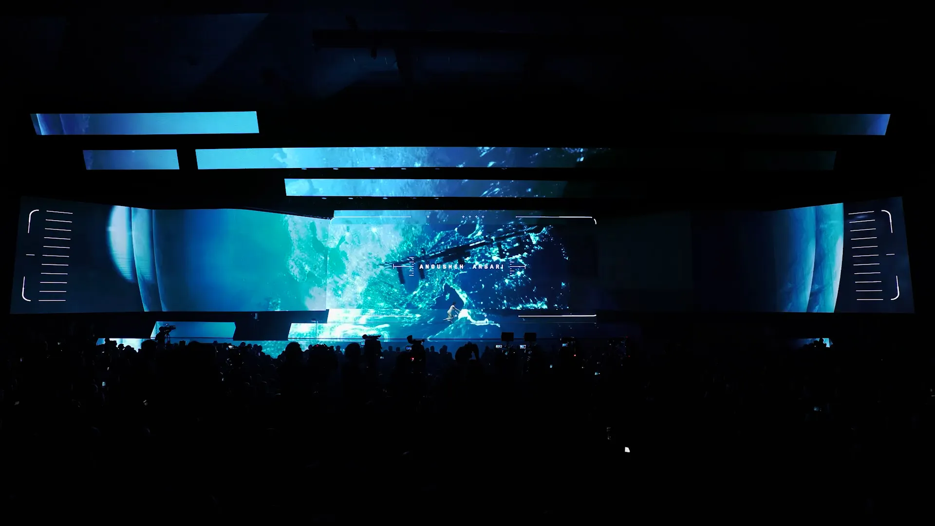 The central screen opens onto deep space, LED bands framing the stage